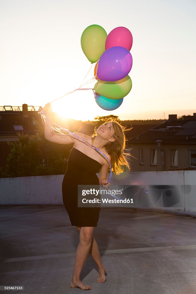 Teenage girl standing with balloons outdoors
