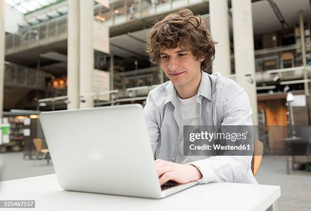 student using laptop in a university library - student laptop stock-fotos und bilder