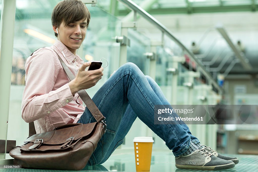 Young man sitting on floor listening to music