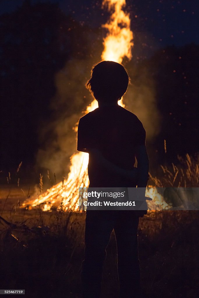 Boy standing in front camp fire at solstice