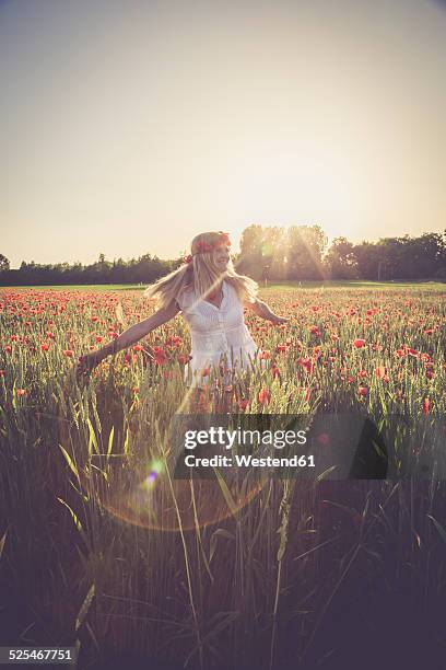 woman dancing in a poppy field at back light - adorno floral fotografías e imágenes de stock