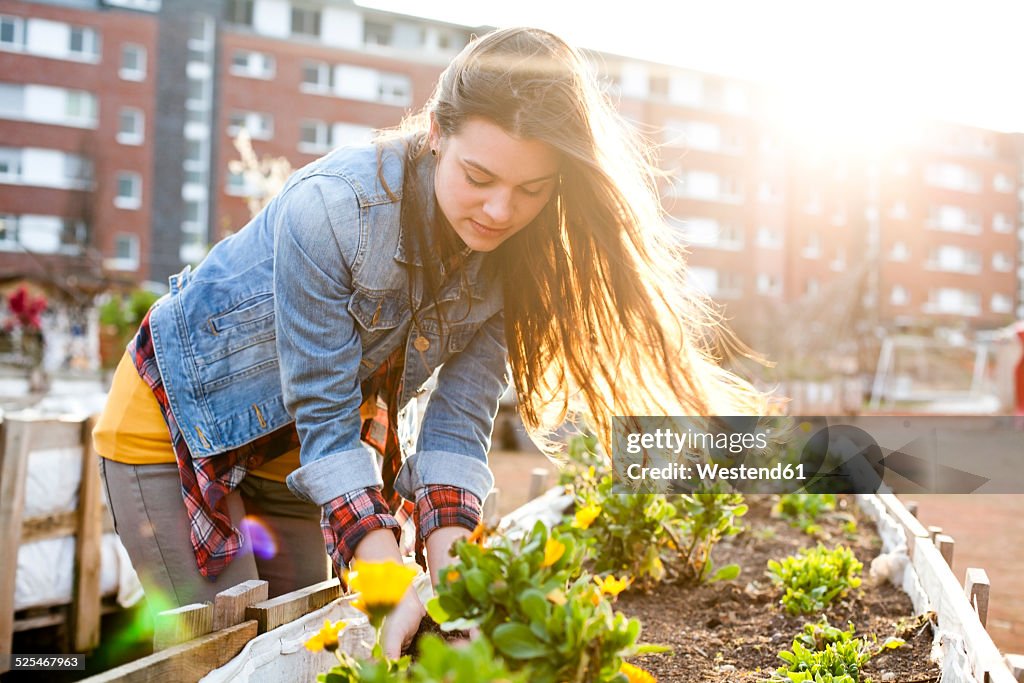 Portrait of young woman at raised bed in front of multi-family house