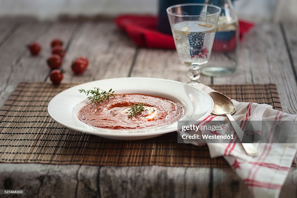 Tomato soup with sour cream, thyme and glass of water