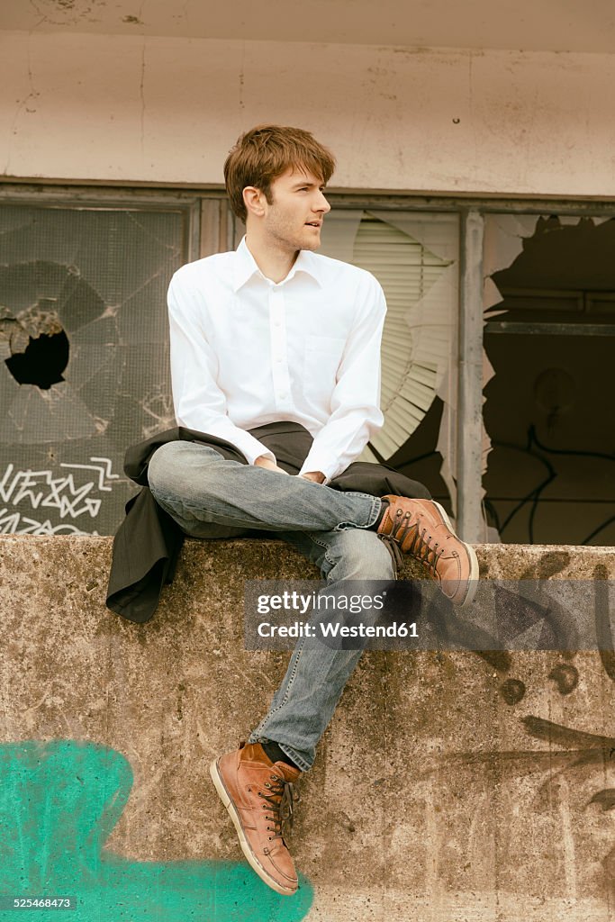 Germany, Hamburg, Hafencity, young man sitting on a wall