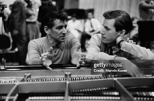 American composer and conductor Leonard Bernstein in conversation with Canadian pianist Glenn Gould at a piano at a Columbia Records recording studio...