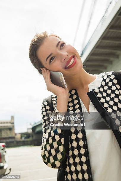 portrait of smiling young woman telephoning with smartphone - tête penchée photos et images de collection