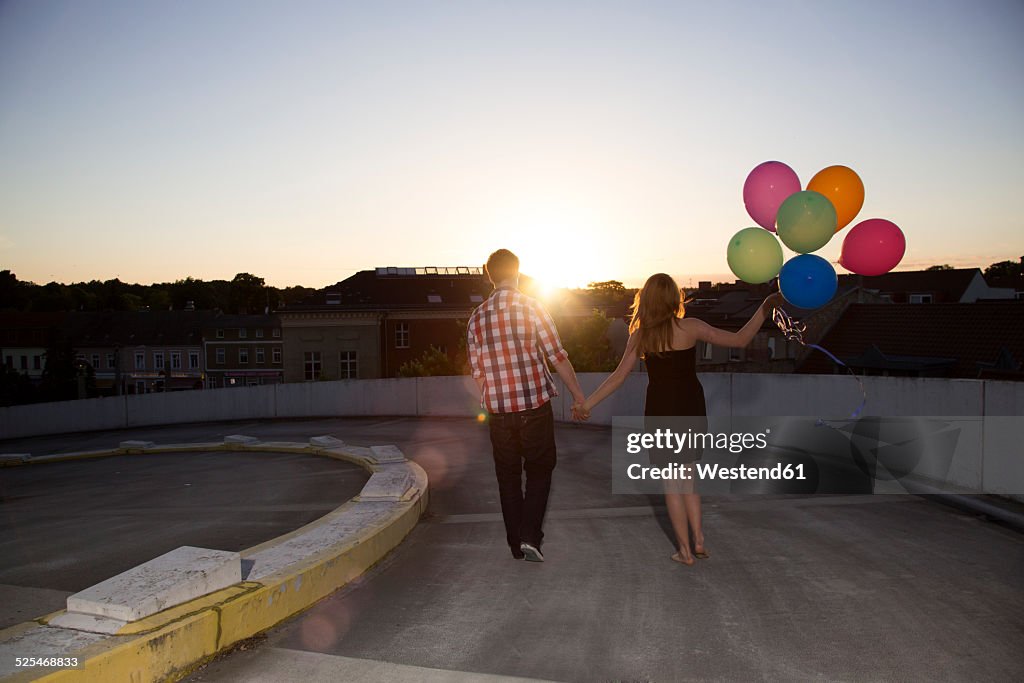 Teenage couple with balloons on parking ramp