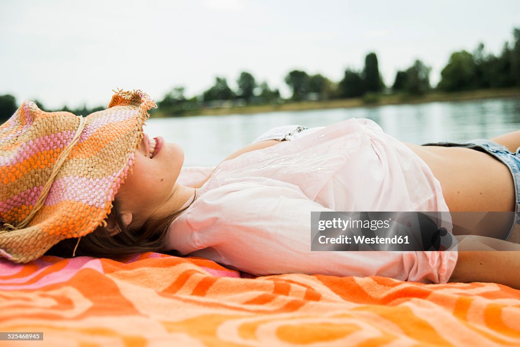 Young woman wearing summer hat relaxing on beach towel