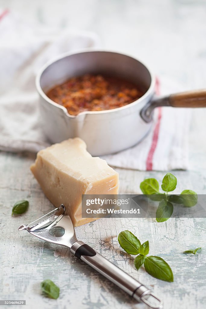 Bolognese sauce in pot, Parmesan cheese and basil leaves