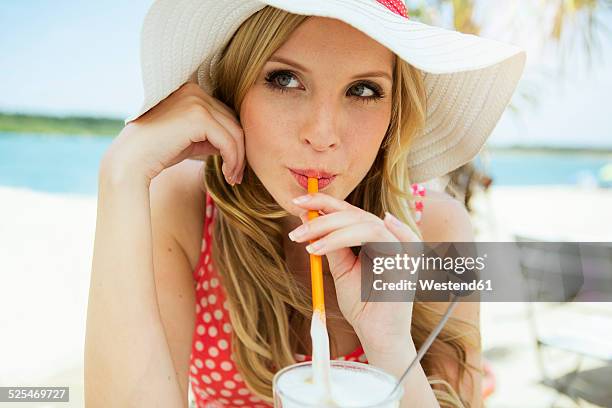 portrait of young woman drinking latte macchiato - zonnehoed stockfoto's en -beelden