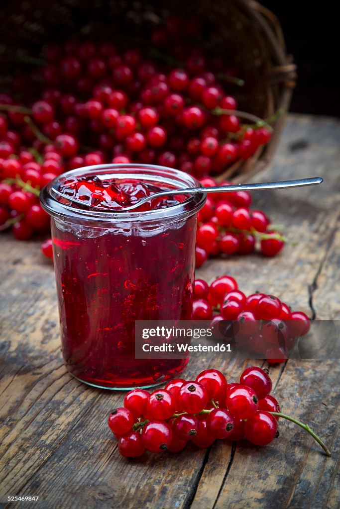 Jam jar of currant jelly and red currants, Ribes rubrum, on wooden table