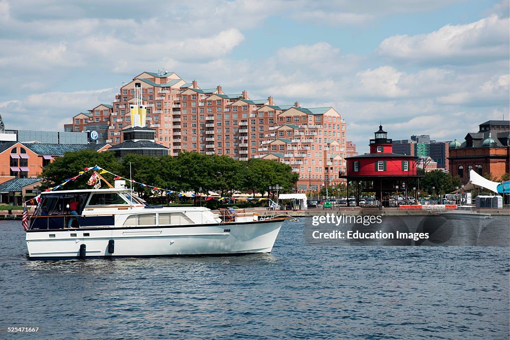 Pleasure boat passes apartment building and old lighthouse in Baltimore harbor, Maryland