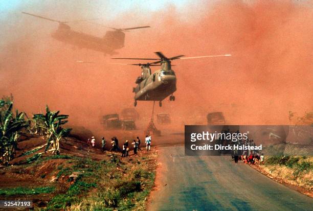 Two Chinook helicopters hover above a road as they assist in evacuating supplies and soldiers of the South Vietnamese 18th Division and their...