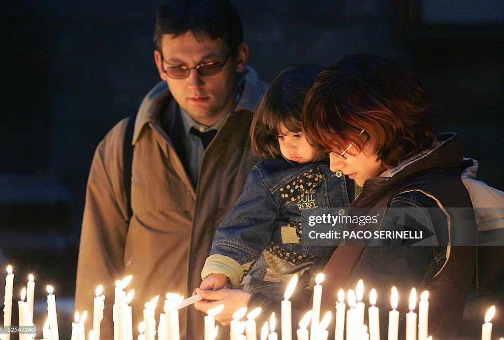A family light a candle as they pray for Pope John Paul II inside the ...