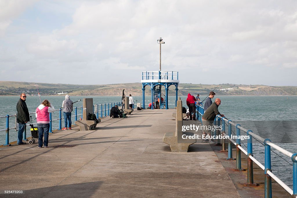 People fishing from harbor breakwater pier at Weymouth, Dorset