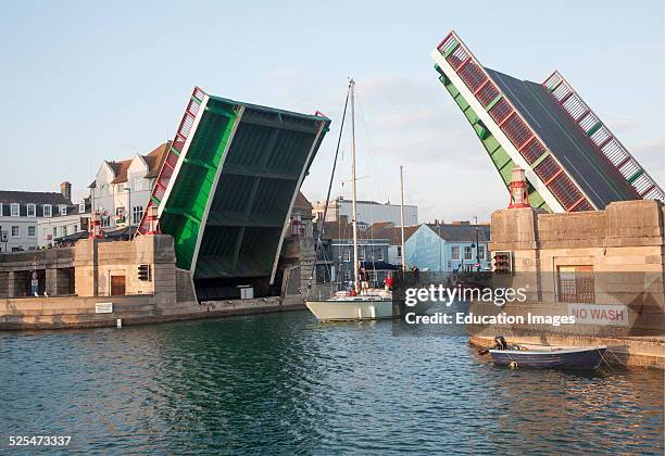 Town bridge raised to allow a yacht to pass into the marina in Weymouth harbor, Dorset, England.
