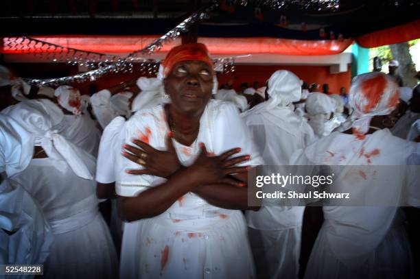 Voodoo believers dance with blood on their white cloth after sacrificing goats during a ritual at the Voodoo temple compound March 27, 2005 at...