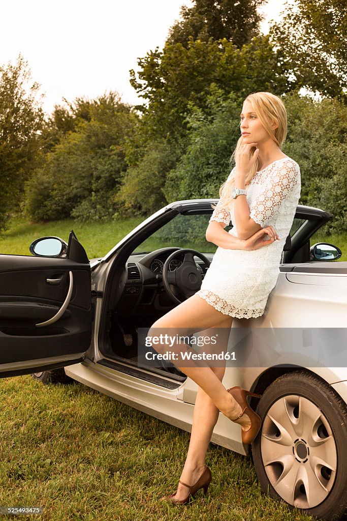 Young woman leaning on cabriolet