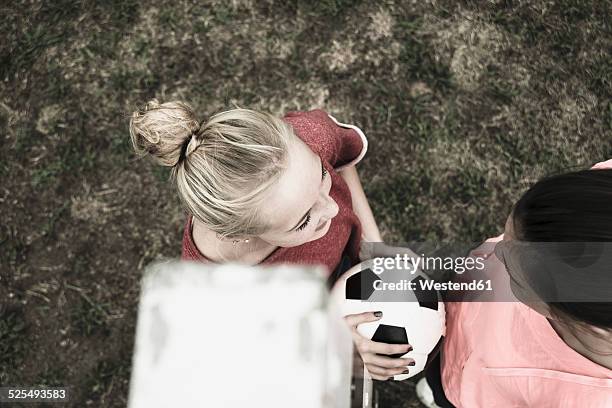 two teenage girls communicating on a football ground, elevated view - minder verzadiging stockfoto's en -beelden