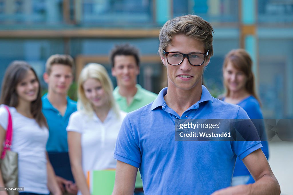 Germany, Baden-Wuertemberg, portrait of young student and his classmates in the background