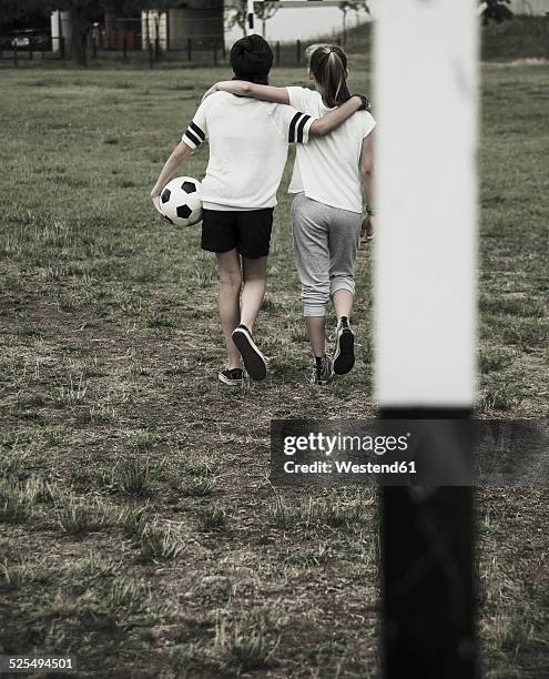 two teenage girls walking on a football ground, back view - デサチュレート ストックフォトと画像