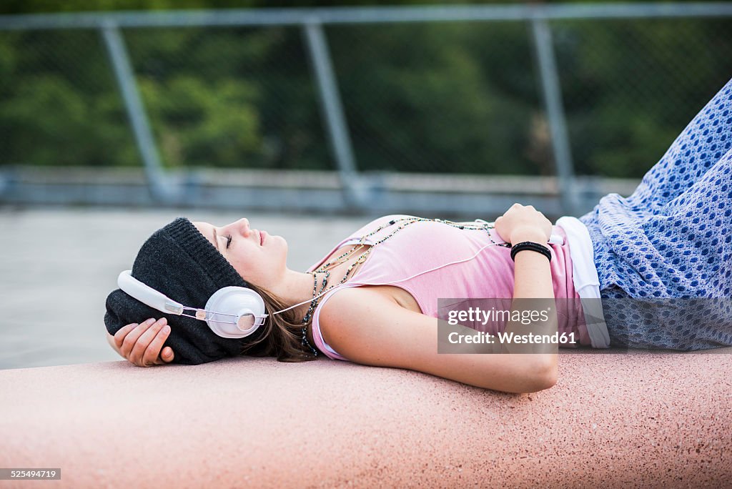 Smiling teenage girl with closed eyes hearing music with headphones