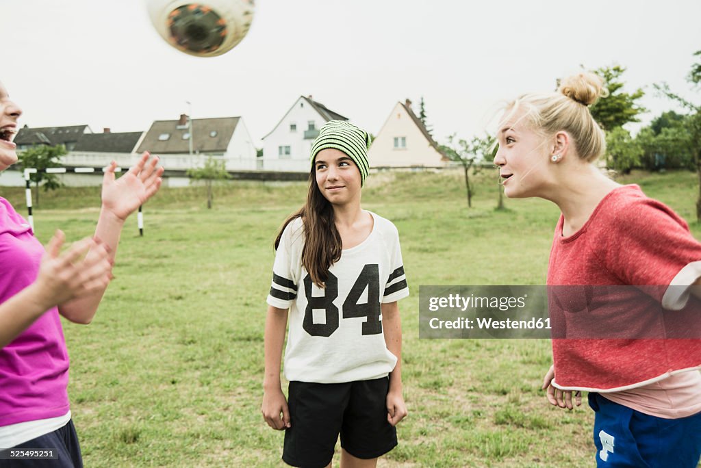 Three teenage girls playing soccer on a football ground