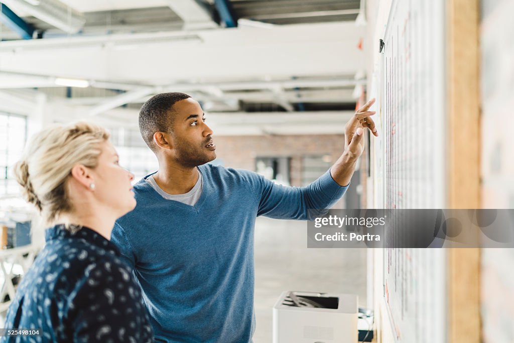 Businessman discussing with colleague over whiteboard