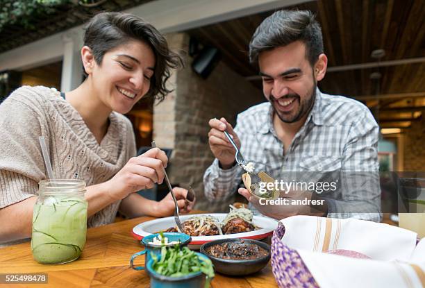 happy couple eating at a restaurant - eating food happy stockfoto's en -beelden