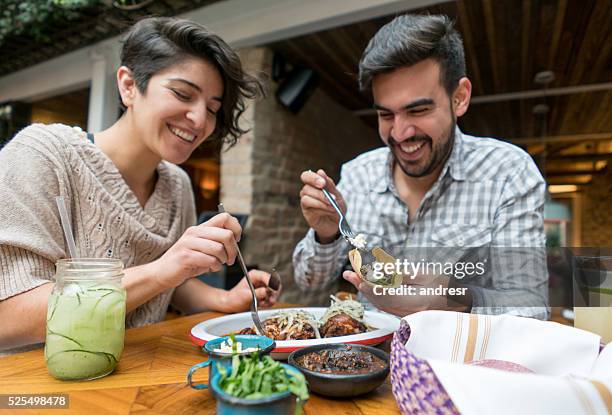 happy couple eating at a restaurant - mexican restaurant stock pictures, royalty-free photos & images