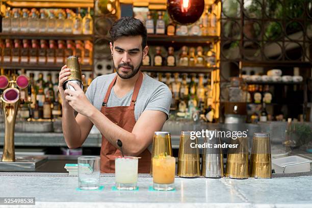 bartender making cocktails at a bar - cocktail shaker stock pictures, royalty-free photos & images