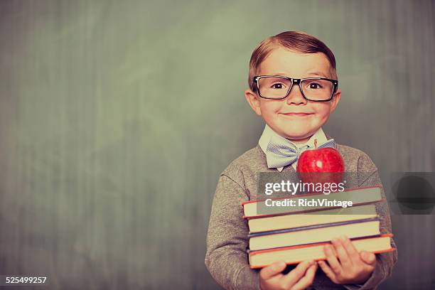 young retro boy holding books in classroom - teachers pet stock pictures, royalty-free photos & images