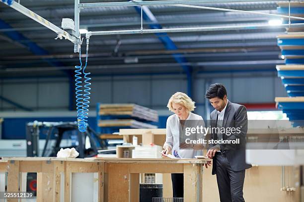 workers looking at paperwork in factory - quality sport images stockfoto's en -beelden