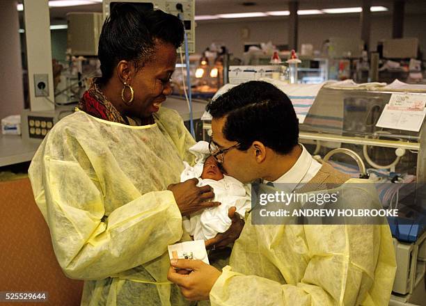 Couple holds and kisses their new premature baby in the intensive medical care section of the neo-natal ward of the Bronx-Lebanon Hospital.