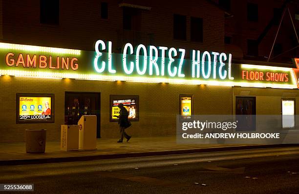 At night, downtown, on Freemont Street, a man passes The El Cortez Hotel and casino, where Bugsy Siegel was a partner.