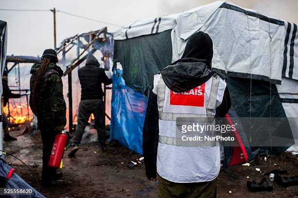An activist of CARE 4 CALAIS helps migrants trying to extinguish the fire during the evacuation of the area south of the jungle. In Calais, France,...