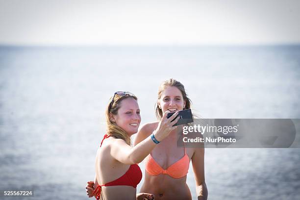 Teenage girls are seen taking selfies at the beach during a hot weather spel on 1st July 2015 in The Hauge, Netherlands.