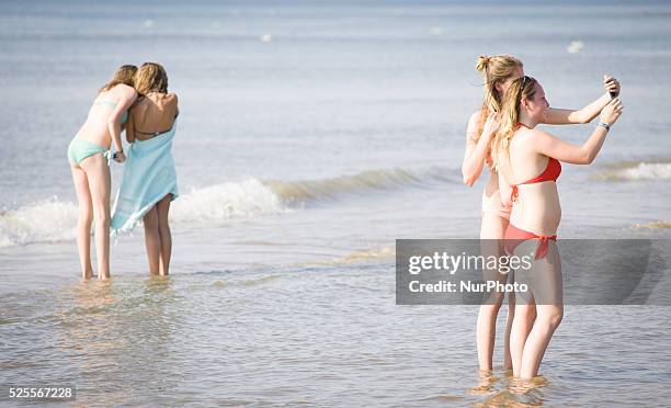 Teenage girls are seen taking selfies at the beach during a hot weather spel on 1st July 2015 in The Hauge, Netherlands.