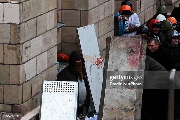 Protesters try to cover themselves from sniper fire under the shields with bloody blur