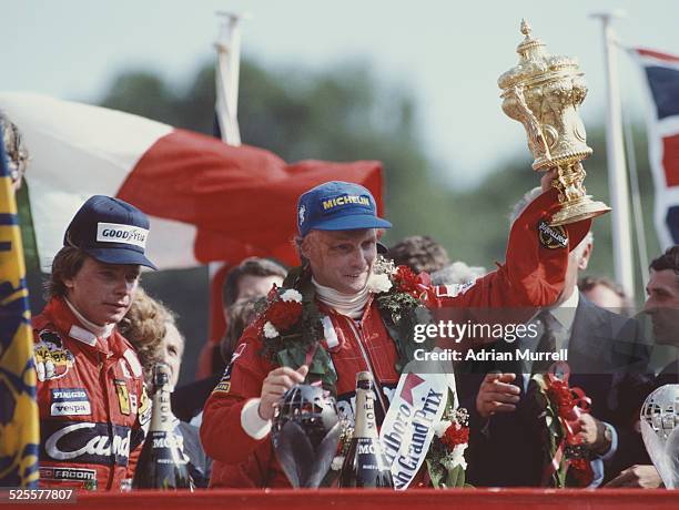 Niki Lauda of Austria and driver of the Marlboro McLaren International McLaren MP4B Ford Cosworth DFV V8 lifts the RAC Trophy and celebrates with...