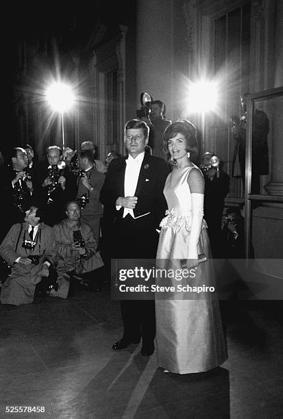 President John F. Kennedy and wife Jacqueline are photographed by the press as they attend a lavish reception.