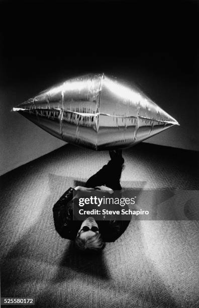 American Pop artist Andy Warhol lies under one of the mylar balloons in his 'Silver Clouds' installation at the Leo Castelli Gallery, New York, New...