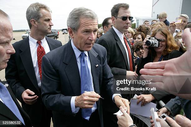 President George W. Bush, center, surrounded by Secret Service agents shakes hands before departing Jackson, Mississippi, after participating in a...