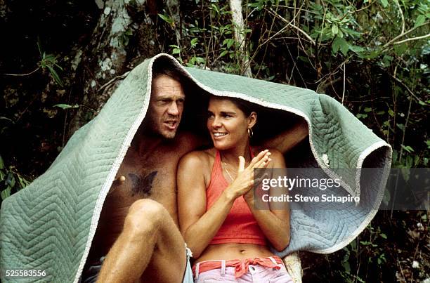 Steve McQueen and girlfriend Ali MacGraw take cover under blanket as it rains on the set of Papillon, on location in Jamaica.