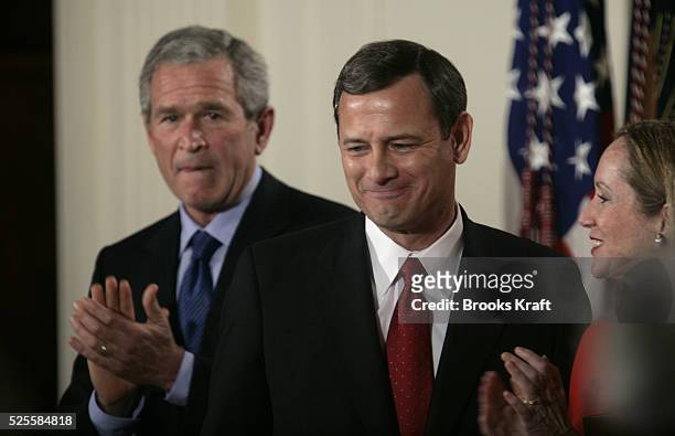 President George W. Bush, left, applauds as John Roberts, center, stands with his wife Jane after he was sworn in as the 17th chief justice of the...
