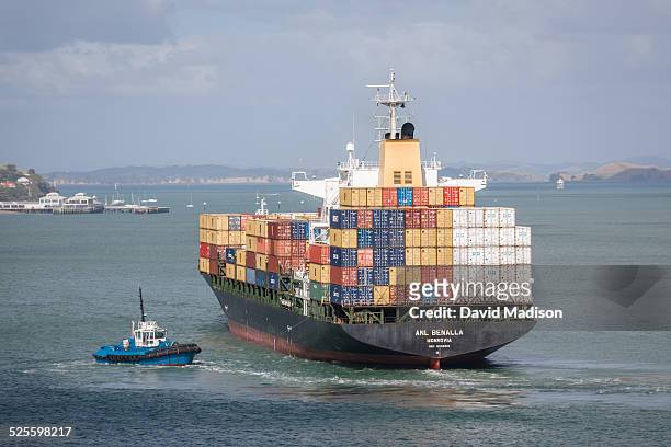 Container cargo ship maneuvers in Auckland Harbor assisted by a tug boat. Auckland, New Zealand, January.