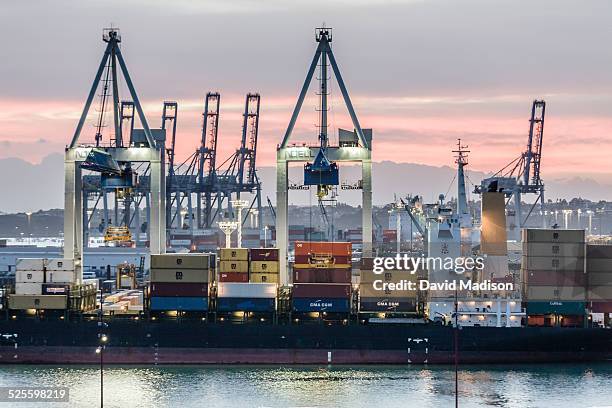 Cargo ship is loaded with cargo containers in the port of Auckland, New Zealand at dawn.