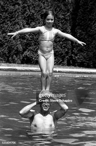 American actress Caley Chase wearing a two-piece swimsuit as she stands on the head of her father, American actor and comedian Chevy Chase who stands...
