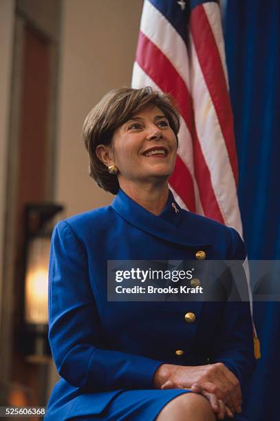 Laura Bush sits in front of the flag in a blue suit. She was in Milwaukee with her husband's Presidential campaign in 2000.