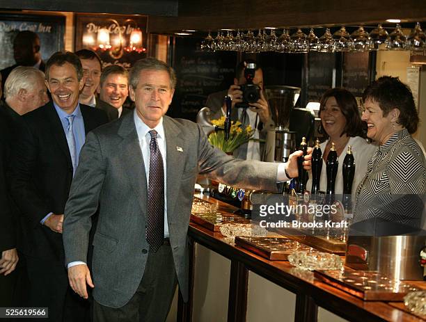 United States President George W. Bush jokes as he pretends to pour a pint of beer alongside British Prime Minister Tony Blair at the Dun Cow pub in...